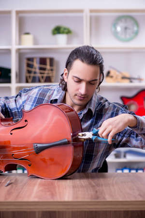 Young handsome repairman repairing celloの写真素材