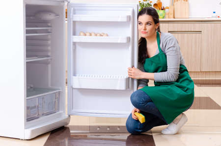 Young woman cleaning fridge in hygiene conceptの写真素材