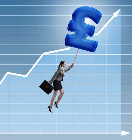 Businesswoman flying on british pound sign inflatable balloonの写真素材