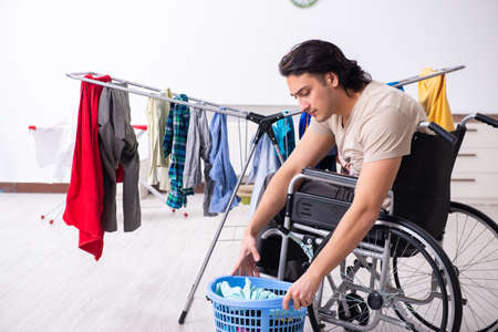 Young man in wheel-chair doing ironing at homeの写真素材