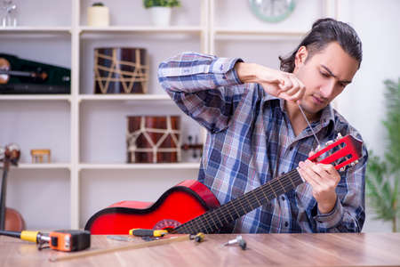 Young handsome repairman repairing guitarの写真素材