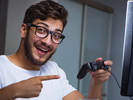 Young man playing games long hours late in the officeの写真素材