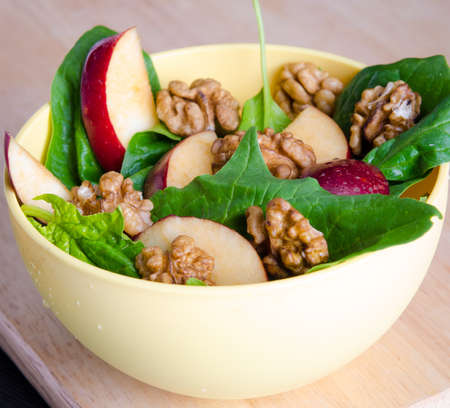 Spinach salad with nuts and apples served on tableの写真素材