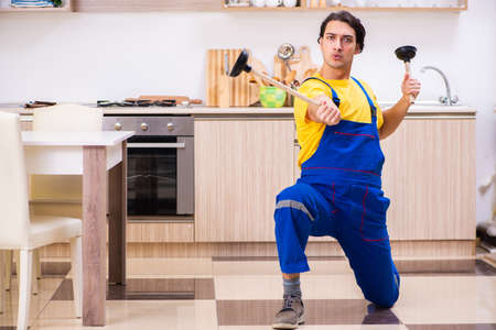 Young male contractor repairing tap at homeの写真素材