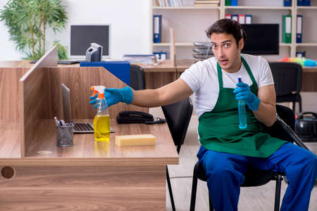 Young handsome contractor cleaning the officeの写真素材