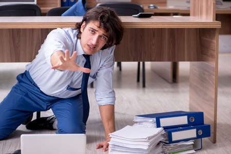 Young male employee and too many work in the officeの写真素材