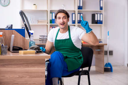 Young handsome contractor cleaning the officeの写真素材