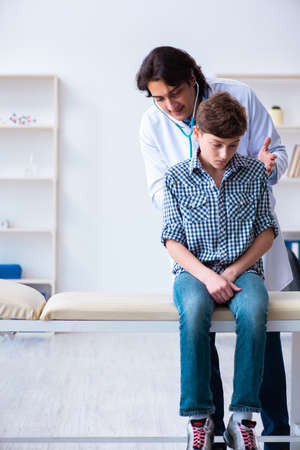 Male doctor examining boy by stethoscopeの写真素材