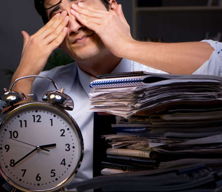 Young businessman working overtime late in officeの写真素材