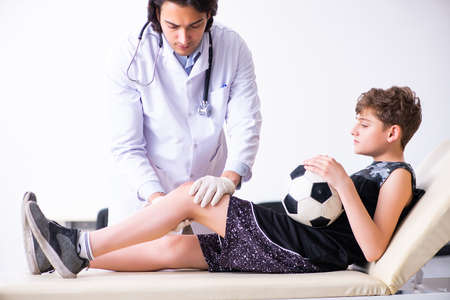 Boy football player visiting young doctor traumatologistの写真素材