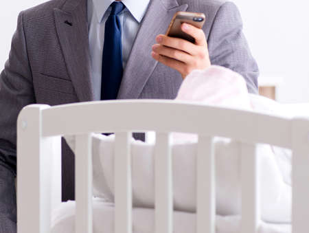 The young businessman trying to work from home caring after newbornの写真素材