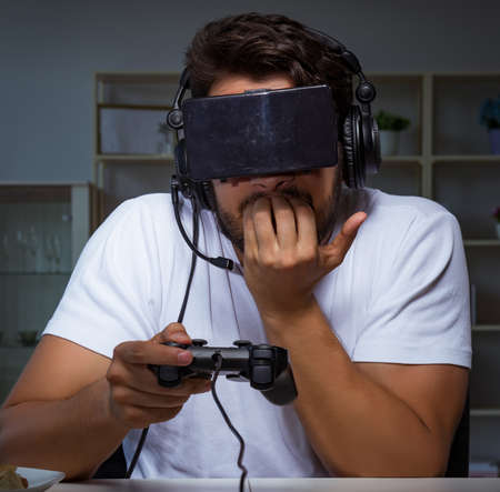 Young man playing games long hours late in the officeの写真素材