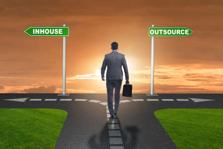 Businessman at crossroads deciding between outsourcing and inhouseの写真素材