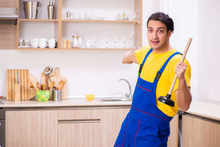 Young male contractor repairing tap at homeの写真素材