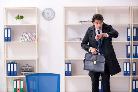 Young male employee in the office in time management conceptの写真素材