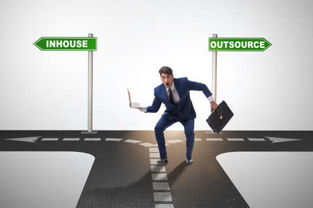 Businessman at crossroads deciding between outsourcing and inhouの写真素材