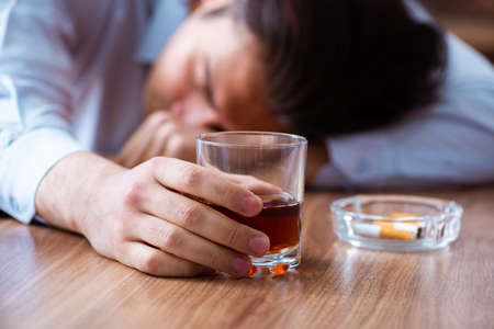 The male employee drinking alcohol and smoking cigarettes at workpla