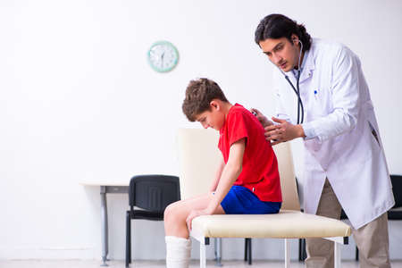 Leg injured boy visiting young doctor traumatologistの写真素材