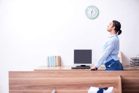 Young handsome businessman doing exercises at workplaceの写真素材