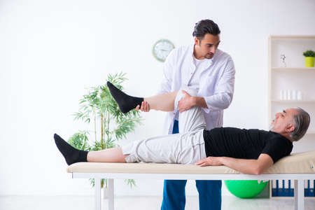 Old injured man visiting young doctorの写真素材