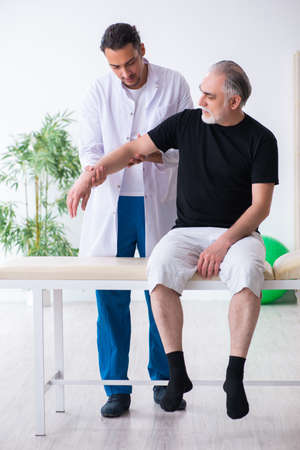 Old injured man visiting young doctorの写真素材
