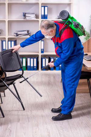 Old professional contractor doing pest control in the officeの写真素材
