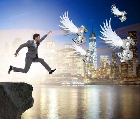 Businessman chasing angel dollars in business conceptの写真素材