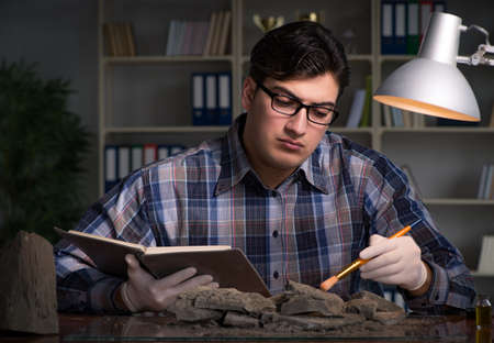Archeologist working late night in officeの写真素材
