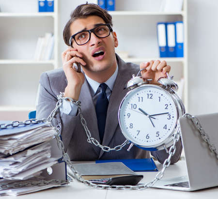 Busy employee chained to his office deskの写真素材