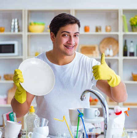 Man showing thumbs up washing dishesの写真素材
