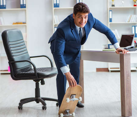 Young businessman with skate in office in sports conceptの写真素材