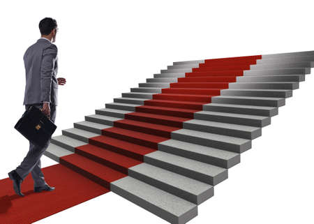 Young businessman climbing stairs and red carpet on white backgroundの写真素材