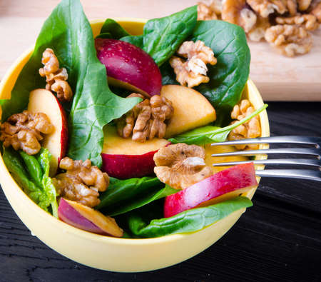 Spinach salad with nuts and apples served on tableの写真素材