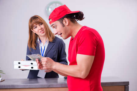 Young male courier delivering pizza to hotels receptionの写真素材