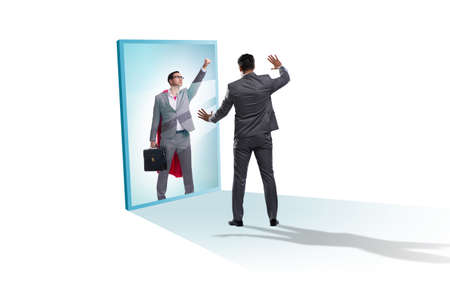 Businessman seeing himself in mirror as superheroの写真素材