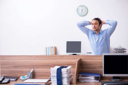 Young handsome businessman doing exercises at workplaceの写真素材