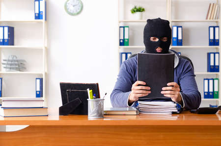 Male thief in balaclava in the officeの写真素材