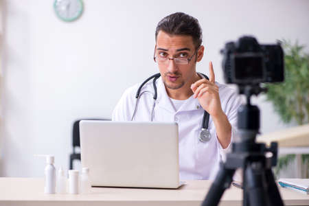 Young male doctor recording video for his blogの写真素材