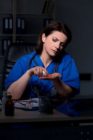 Aged female doctor working at night shiftの写真素材