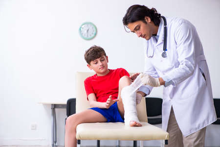 Leg injured boy visiting young doctor traumatologistの写真素材