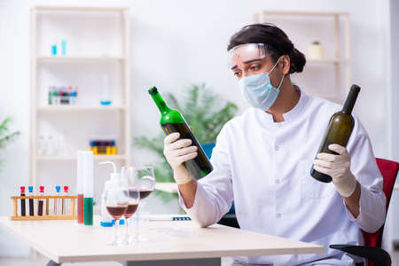 Male chemist examining wine samples at labの写真素材