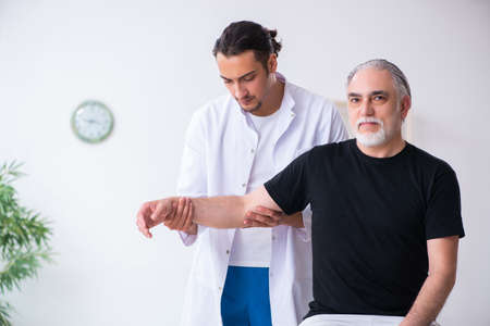 Old injured man visiting young doctorの写真素材