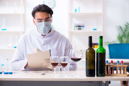 Male chemist examining wine samples at labの写真素材