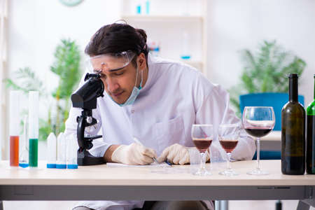 Male chemist examining wine samples at labの写真素材