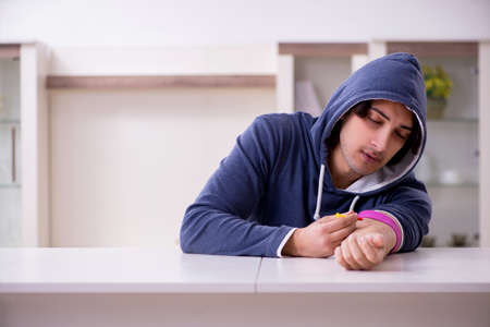 Young man having problems with narcotics at homeの写真素材