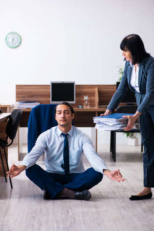Male employee doing yoga exercises in the officeの写真素材