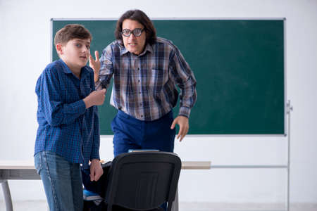 Funny male teacher and boy in the classroomの写真素材
