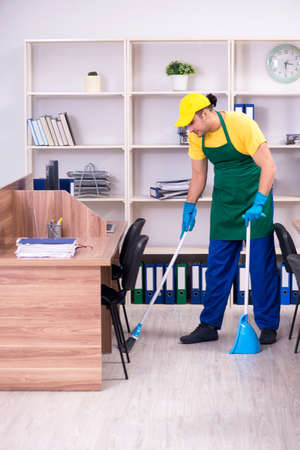 Young male contractor cleaning the officeの写真素材