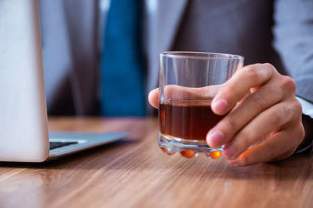 Male employee drinking alcohol and smoking cigarettes at workpla