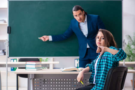 Young handsome teacher and female student in the classroomの写真素材